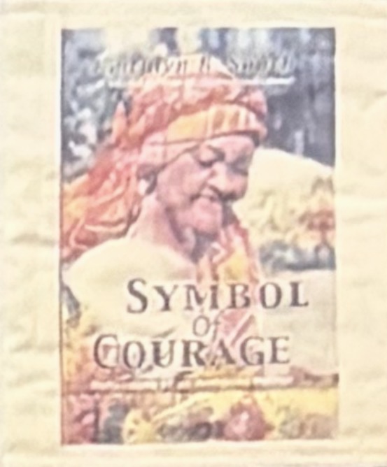 Quilt panel reproducing the book's cover: a portrait of elder Mary Lewis-Peterson in an orange and yellow headwrap above title lettering, on cream textured cloth