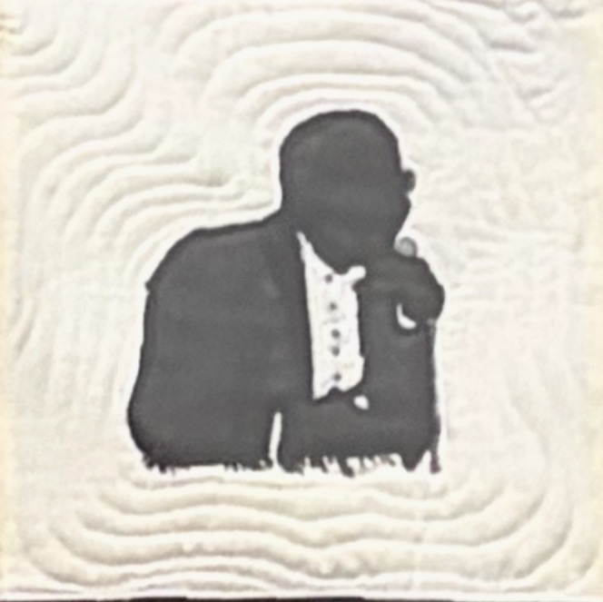 Quilted panel depicting a silhouette of a man in a tuxedo with hand raised in reflection, set against a cream textured background with concentric stitched ripples